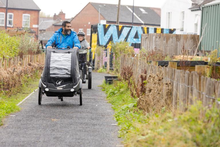 People cycle on cargo bikes along path