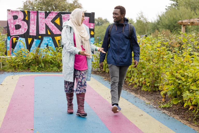 Two pedestrians walk on colourful path